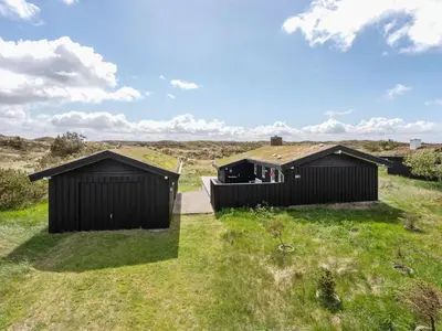two black huts in a field with grass at Holiday Home Driss - 500m from the sea by Interhome in Pandrup