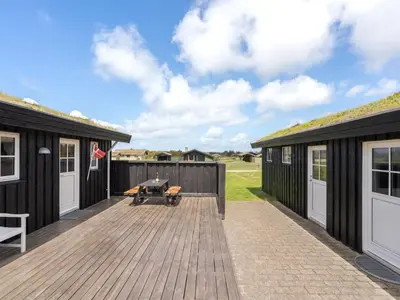 a deck with two buildings and a picnic table at Holiday Home Driss - 500m from the sea by Interhome in Pandrup