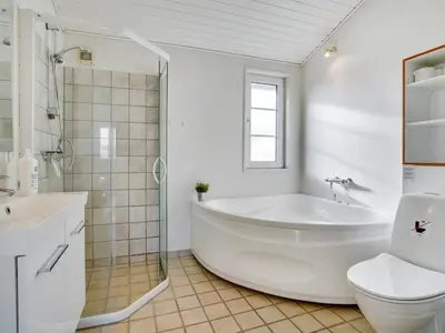 a white bathroom with a tub and a toilet at Holiday Home Zaharinka - 300m from the sea by Interhome in Pandrup