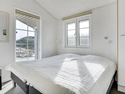 a white bedroom with a large bed and windows at Holiday Home Zaharinka - 300m from the sea by Interhome in Pandrup