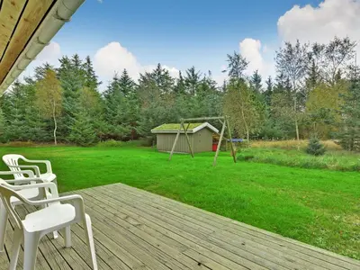 a deck with two white chairs and a playground at Holiday Home Editt - 2km from the sea by Interhome in Pandrup