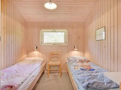 a bedroom with two beds and a chair in it at Holiday Home Editt - 2km from the sea by Interhome in Pandrup