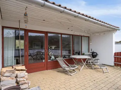 a patio with chairs and a table and a grill at Holiday Home Viena - 400m from the sea by Interhome in Pandrup