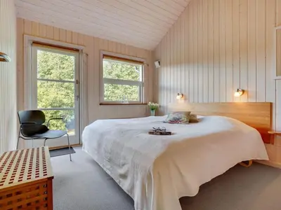 a bedroom with a large bed and a chair at Holiday Home Krister - 250m to the fjord by Interhome in Farsø