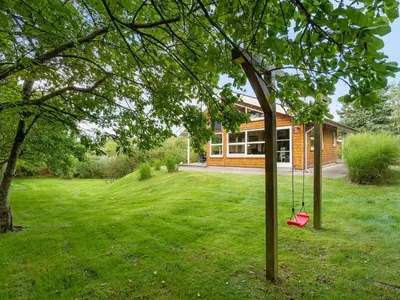 a house with a tree with a swing in the yard at Holiday Home Krister - 250m to the fjord by Interhome in Farsø