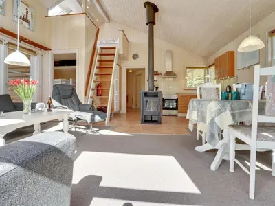 a living room with a table and a kitchen at Holiday Home Krister - 250m to the fjord by Interhome in Farsø