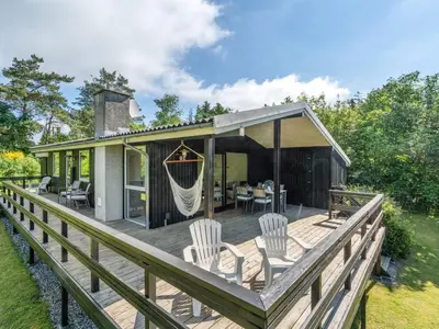 a house with a deck with chairs and a hammock at Holiday Home Angantir - 700m to the fjord by Interhome in Løgstør