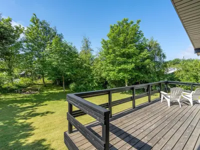 a wooden deck with two chairs and trees at Holiday Home Angantir - 700m to the fjord by Interhome in Løgstør