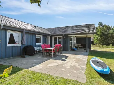 a house with a table and chairs and a surfboard at Holiday Home Awenita - 50m to the fjord by Interhome in Løgsted