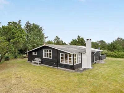 a black cabin with a bench in a yard at Holiday Home Githa - 100m to the fjord by Interhome in Løgstør