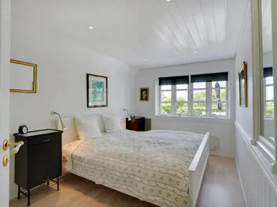 a white bedroom with a bed and a window at Holiday Home Tamer - 500m to the fjord by Interhome in Farsø