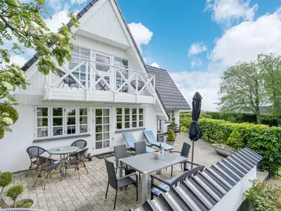 a patio with chairs and tables in front of a house at Holiday Home Tamer - 500m to the fjord by Interhome in Farsø