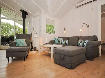 a living room with a couch and a table and chairs at Holiday Home Evelina - 150m to the fjord by Interhome in Løgsted