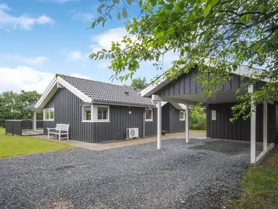 a black house with a bench in front of it at Holiday Home Evelina - 150m to the fjord by Interhome in Løgsted