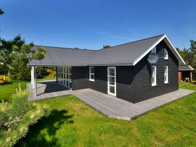 a black house with a deck in a yard at Holiday Home Anethe - 100m to the fjord by Interhome in Løgstør
