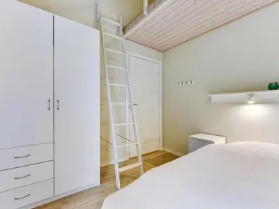 a bedroom with a white bed and a ladder at Holiday Home Anethe - 100m to the fjord by Interhome in Løgstør