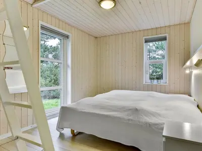 a bedroom with a bed and two windows at Holiday Home Anethe - 100m to the fjord by Interhome in Løgstør