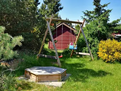 a swing set in a yard with a red cabin at Holiday Home Anethe - 100m to the fjord by Interhome in Løgstør