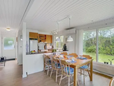 a kitchen and dining room with a wooden table and chairs at Holiday Home Thina - 750m to the fjord by Interhome in Løgsted