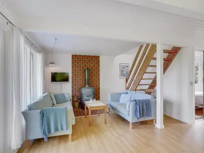 a living room with two blue chairs and a tv at Holiday Home Thina - 750m to the fjord by Interhome in Løgsted