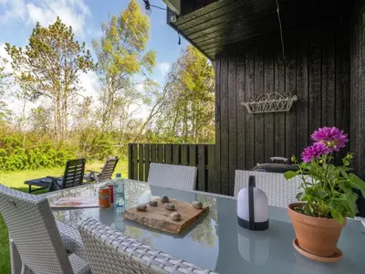 a patio with a table with chairs and flowers at Holiday Home Thina - 750m to the fjord by Interhome in Løgsted
