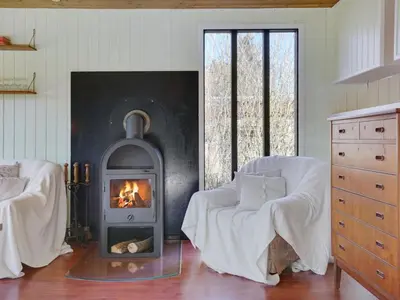 a living room with a fireplace and a couch and a chair at Holiday Home Ludde - 500m to the fjord by Interhome in Løgstør