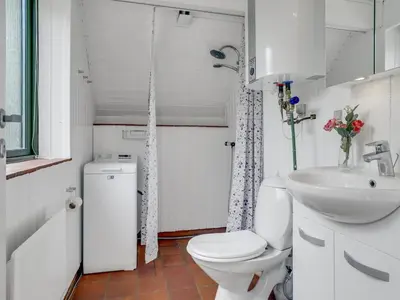 a white bathroom with a toilet and a sink at Holiday Home Valo - 400m to the fjord by Interhome in Løgsted