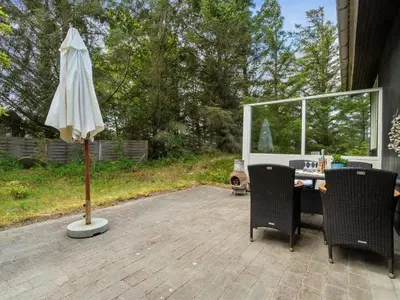an umbrella and a table and chairs on a patio at Holiday Home Freda - 100m to the fjord by Interhome in Løgsted