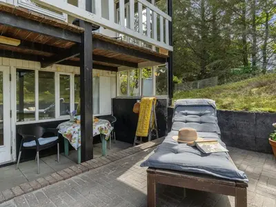 a patio with a bed and a table with a hat on it at Holiday Home Freda - 100m to the fjord by Interhome in Løgsted