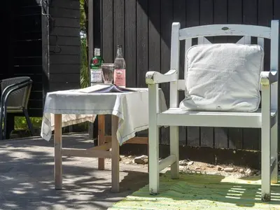 a white chair with a table and a bottle at Holiday Home Freda - 100m to the fjord by Interhome in Løgsted