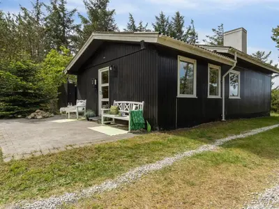 a black tiny house with a porch and a patio at Holiday Home Freda - 100m to the fjord by Interhome in Løgsted