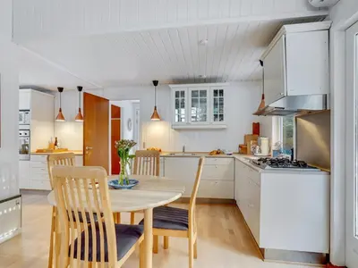 a kitchen with a table and chairs in a kitchen at Holiday Home Freda - 100m to the fjord by Interhome in Løgsted