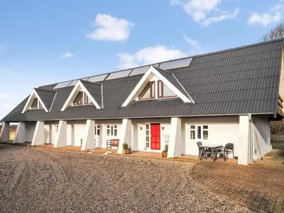 a white house with a black roof with a red door at Holiday Home Millie - 3km to the fjord by Interhome in Løgstør