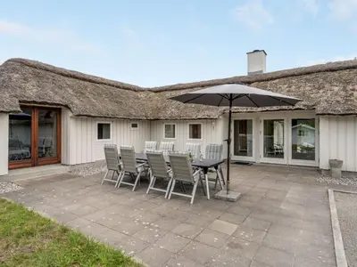 a patio with a table and chairs and an umbrella at Holiday Home Waldar - 900m from the sea by Interhome in Fjerritslev