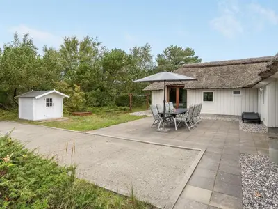 a patio with a table and an umbrella at Holiday Home Waldar - 900m from the sea by Interhome in Fjerritslev