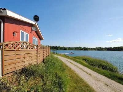 a red house with a fence next to a dirt road at Holiday Home Alvira - 8km to the fjord by Interhome in Fjerritslev