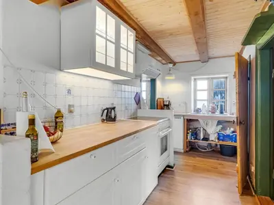 a kitchen with white cabinets and a wooden counter top at Holiday Home Agrippa - 30m to the fjord by Interhome in Løgstør