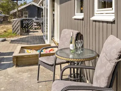 a table with two chairs and a bottle of wine at Holiday Home Sighbiorn - 950m from the sea by Interhome in Fjerritslev