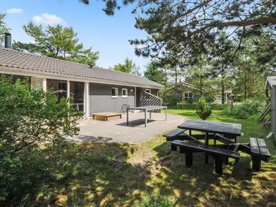 a picnic table and bench in front of a building at Holiday Home Sighbiorn - 950m from the sea by Interhome in Fjerritslev