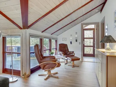 a living room with a table and chairs and windows at Holiday Home Thurir - 4km from the sea by Interhome in Fjerritslev