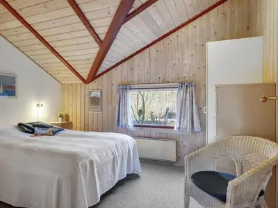 a bedroom with a bed and a chair and a window at Holiday Home Thurir - 4km from the sea by Interhome in Fjerritslev