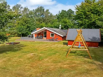 a red house with a playground in front of it at Holiday Home Thurir - 4km from the sea by Interhome in Fjerritslev