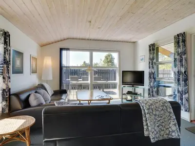 a living room with a black couch and a tv at Holiday Home Ordan - 800m from the sea by Interhome in Fjerritslev