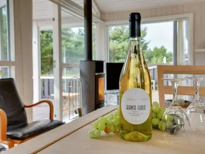 a bottle of wine sitting on a table with grapes at Holiday Home Gothfred - 1km from the sea by Interhome in Fjerritslev
