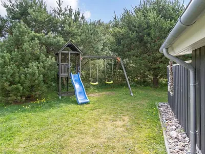 a playground with a slide in a yard at Holiday Home Gothfred - 1km from the sea by Interhome in Fjerritslev