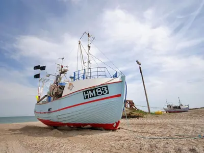 a boat sitting on the sand on the beach at Holiday Home Gothfred - 1km from the sea by Interhome in Fjerritslev