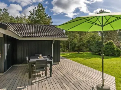 a patio with a table and a green umbrella at Holiday Home Grimi - 4km from the sea by Interhome in Fjerritslev