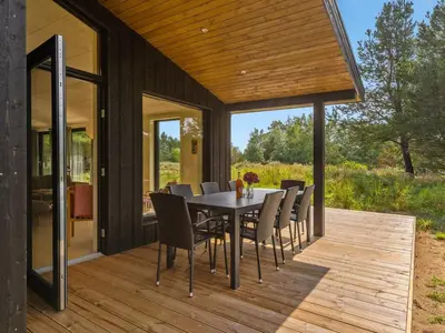 a dining room with a table and chairs on a deck at Holiday Home Vigga - 800m from the sea by Interhome in Fjerritslev