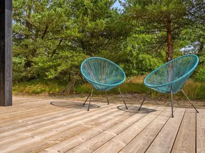 two blue chairs sitting on top of a wooden deck at Holiday Home Vigga - 800m from the sea by Interhome in Fjerritslev