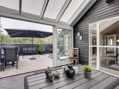 a screened porch with an umbrella and a patio at Holiday Home Henriete - 3-5km from the sea by Interhome in Fjerritslev